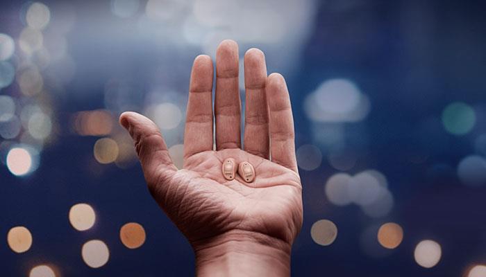 Eine Hand, die praktisch unsichtbare ReSound LiNX Quattro Hörsysteme hält