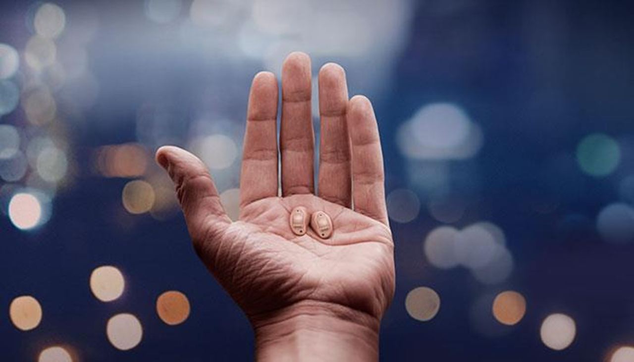 Una mano sujetando los audífonos ReSound LiNX Quattro prácticamente invisibles