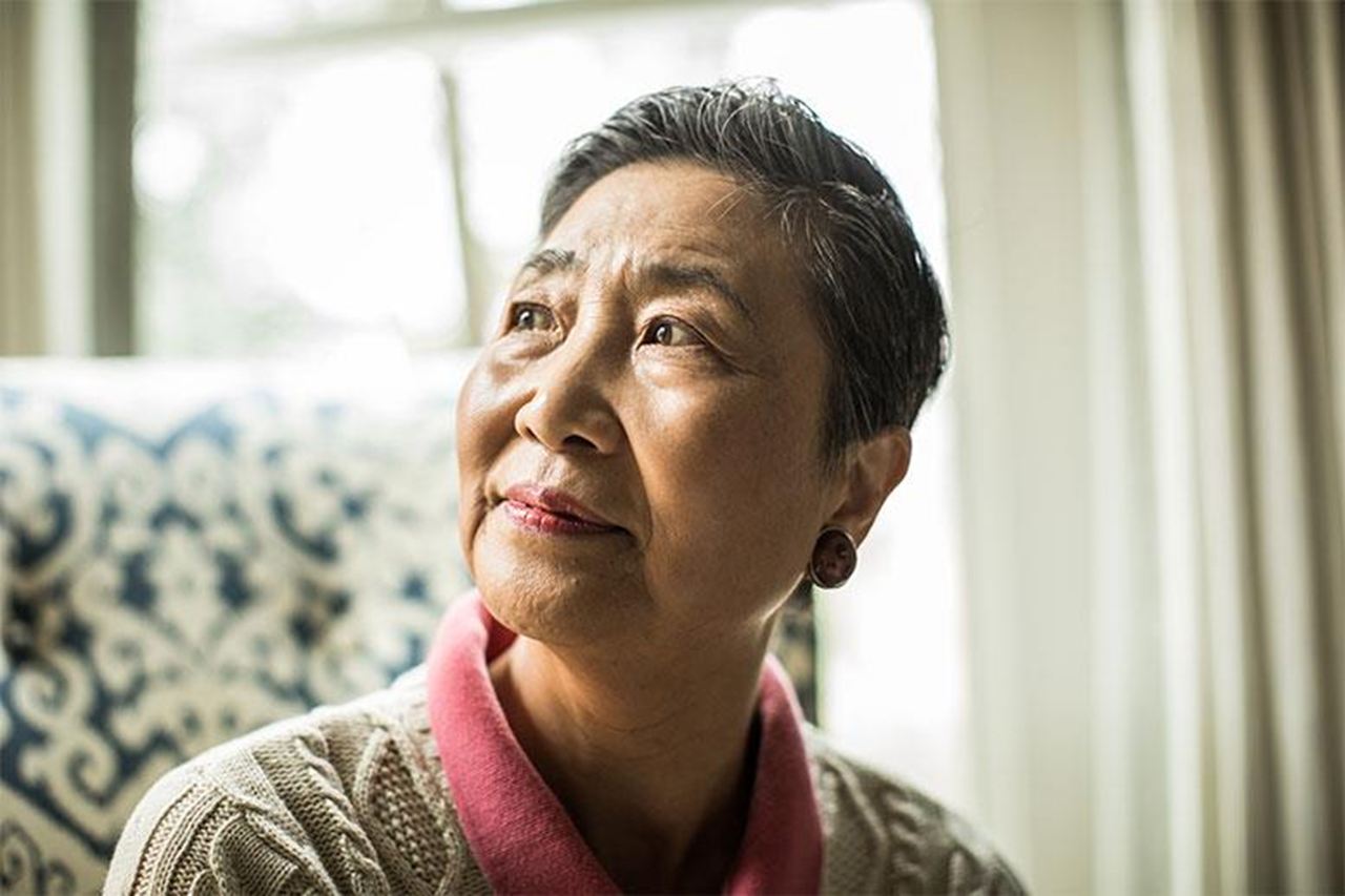 En ældre dame, der sidder ved et vindue