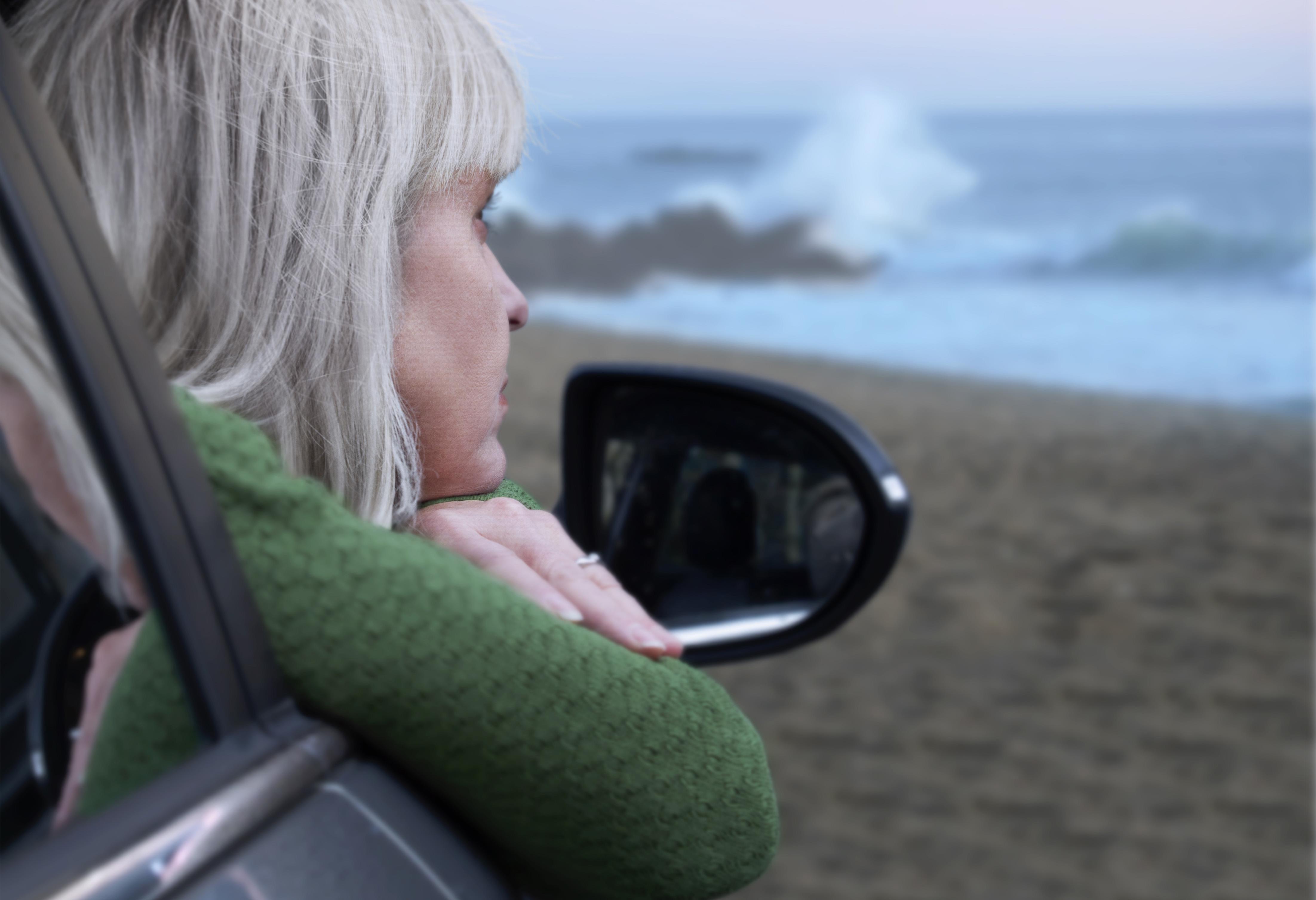 Mulher na praia parece pensativa.