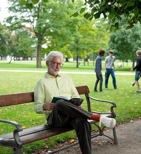 Hombre leyendo en un banco en un parque
