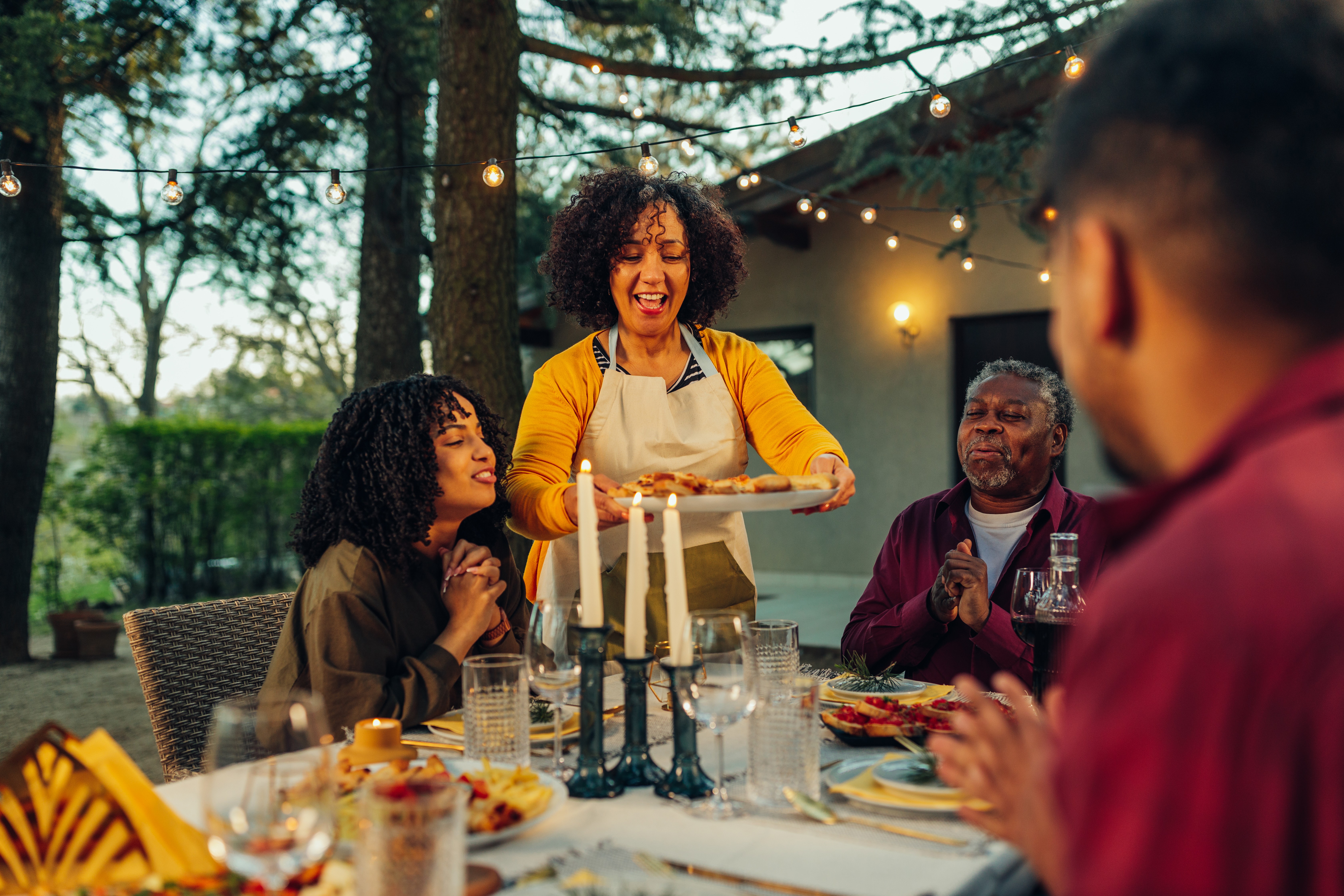 Family enjoying an outdoor dinner together under string lights